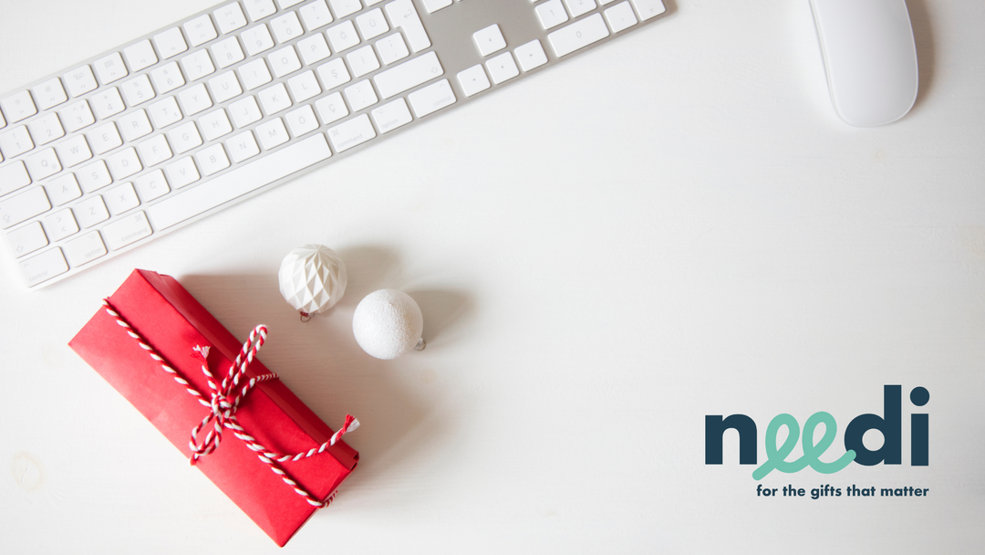 A  beautifully wrapped, personalised corporate christmas gift sits next to a keyboard and mouse on a desk waiting to be opened
