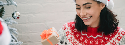 A woman opens a Christmas present from needi.co.uk