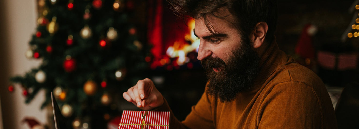 A man opens a Christmas present from needi.co.uk