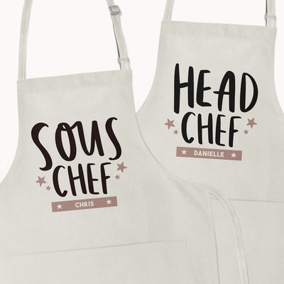 Matching Couple Gifts Personalised Apron Set Chefs Bakers reads 'Sous Chef [name]' and 'Head Chef [name]'